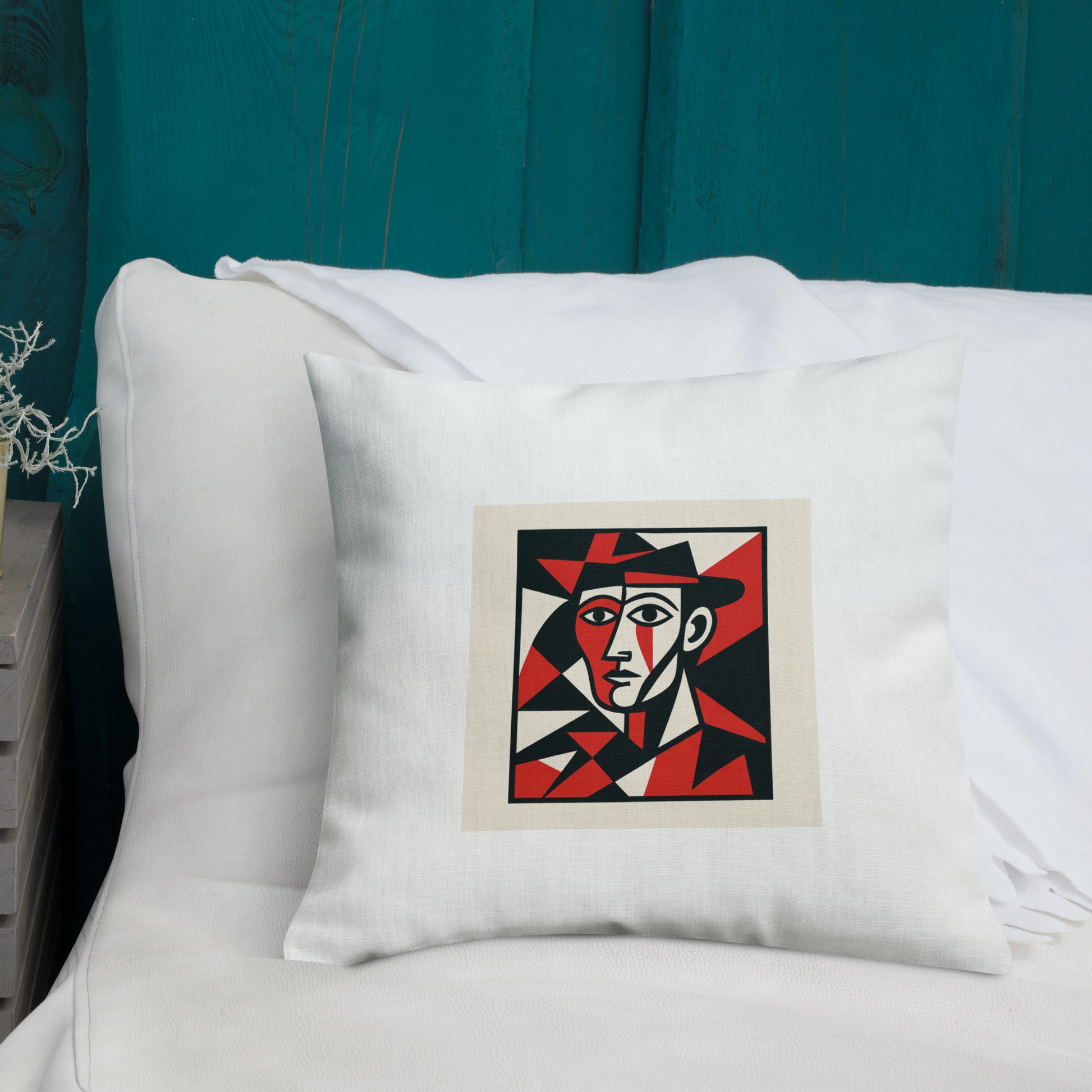 Decorative pillow with geometric face design on a white couch against a teal wall.