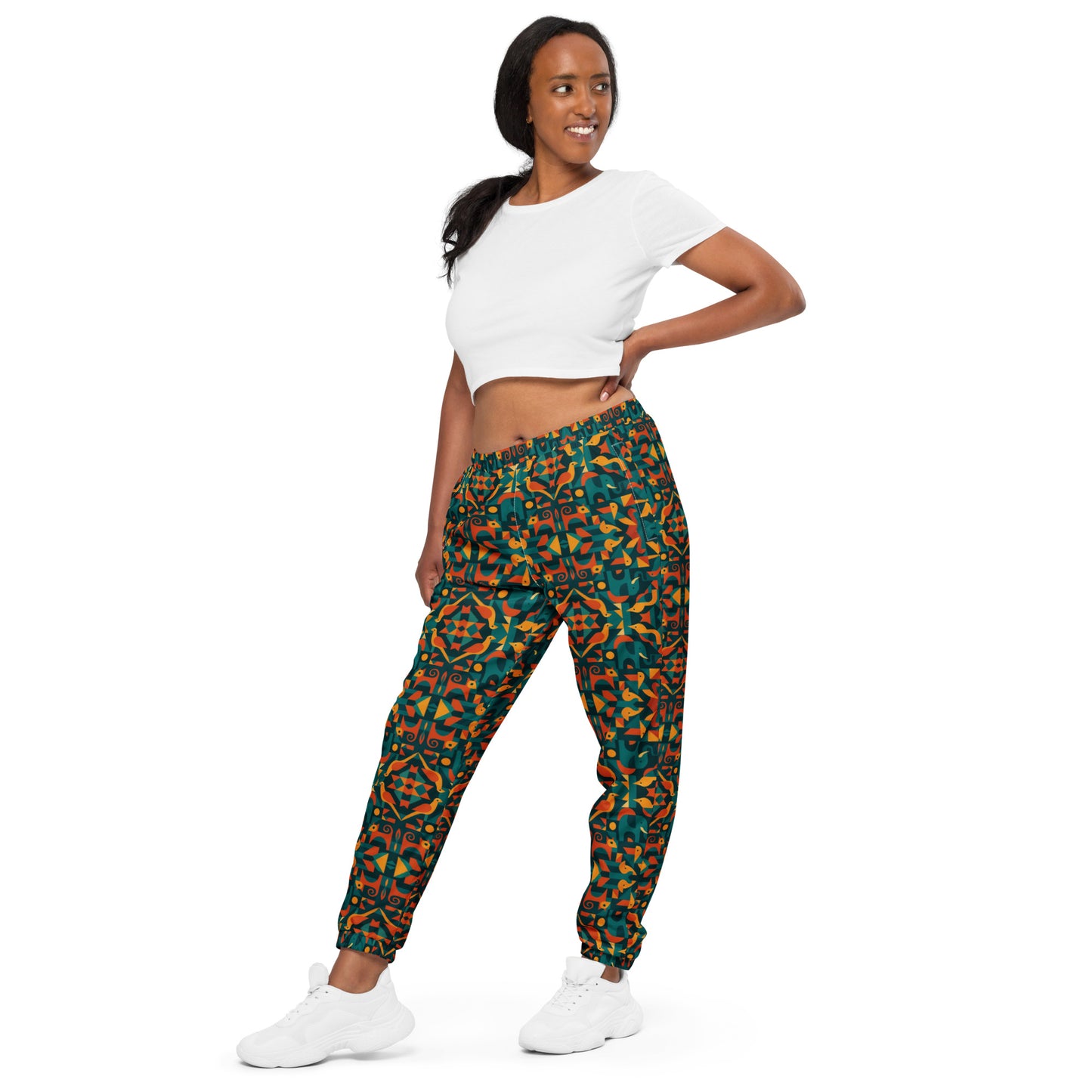 Woman wearing colorful patterned pants and a white crop top on a white background