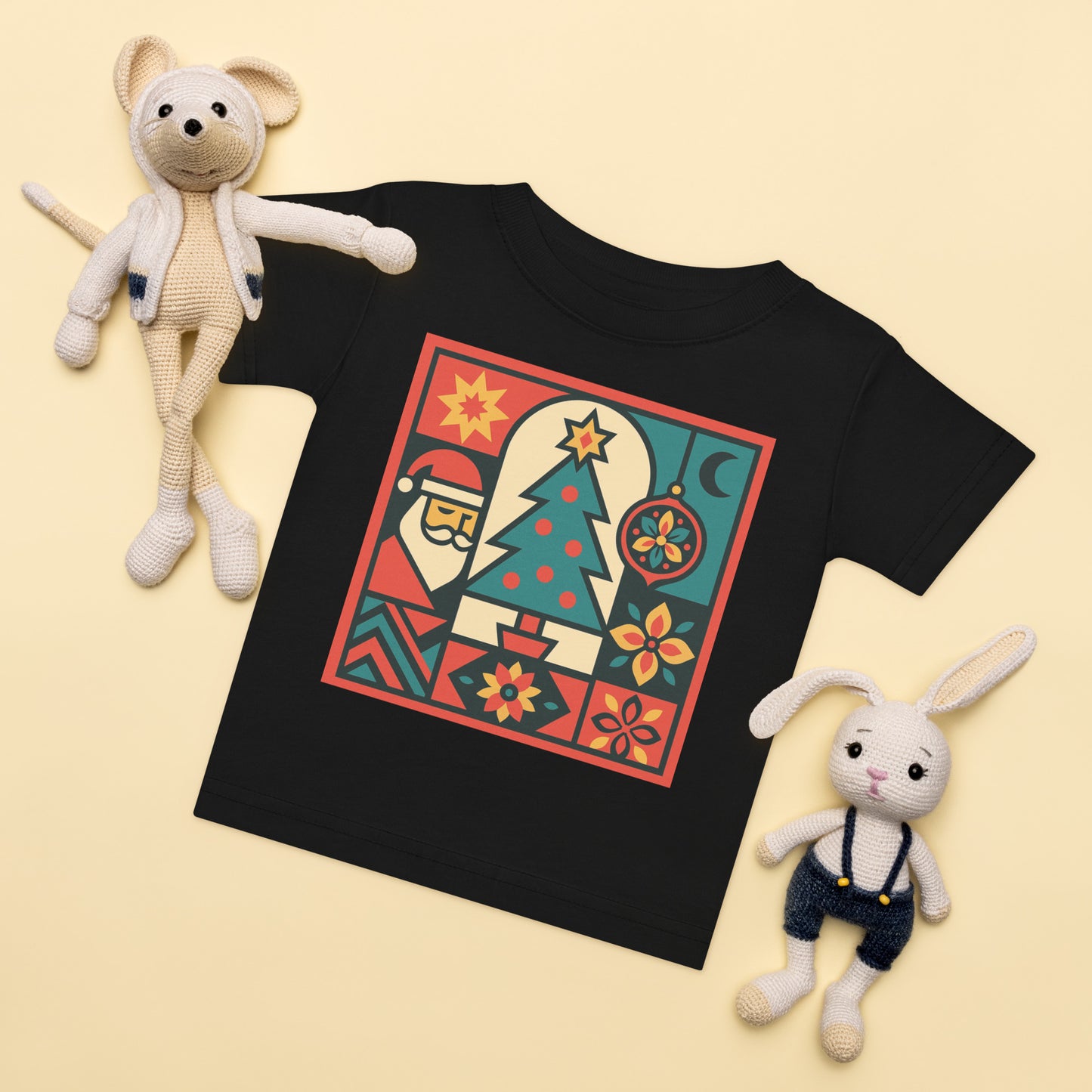 Black t-shirt with colorful graphic design, surrounded by two plush toys on a beige background