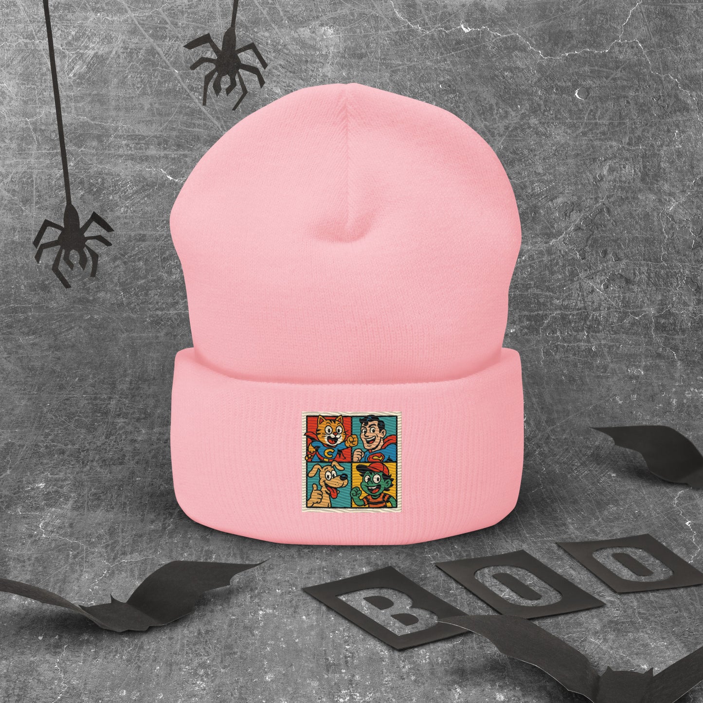 Pink beanie with a colorful graphic on a gray background with Halloween decorations.
