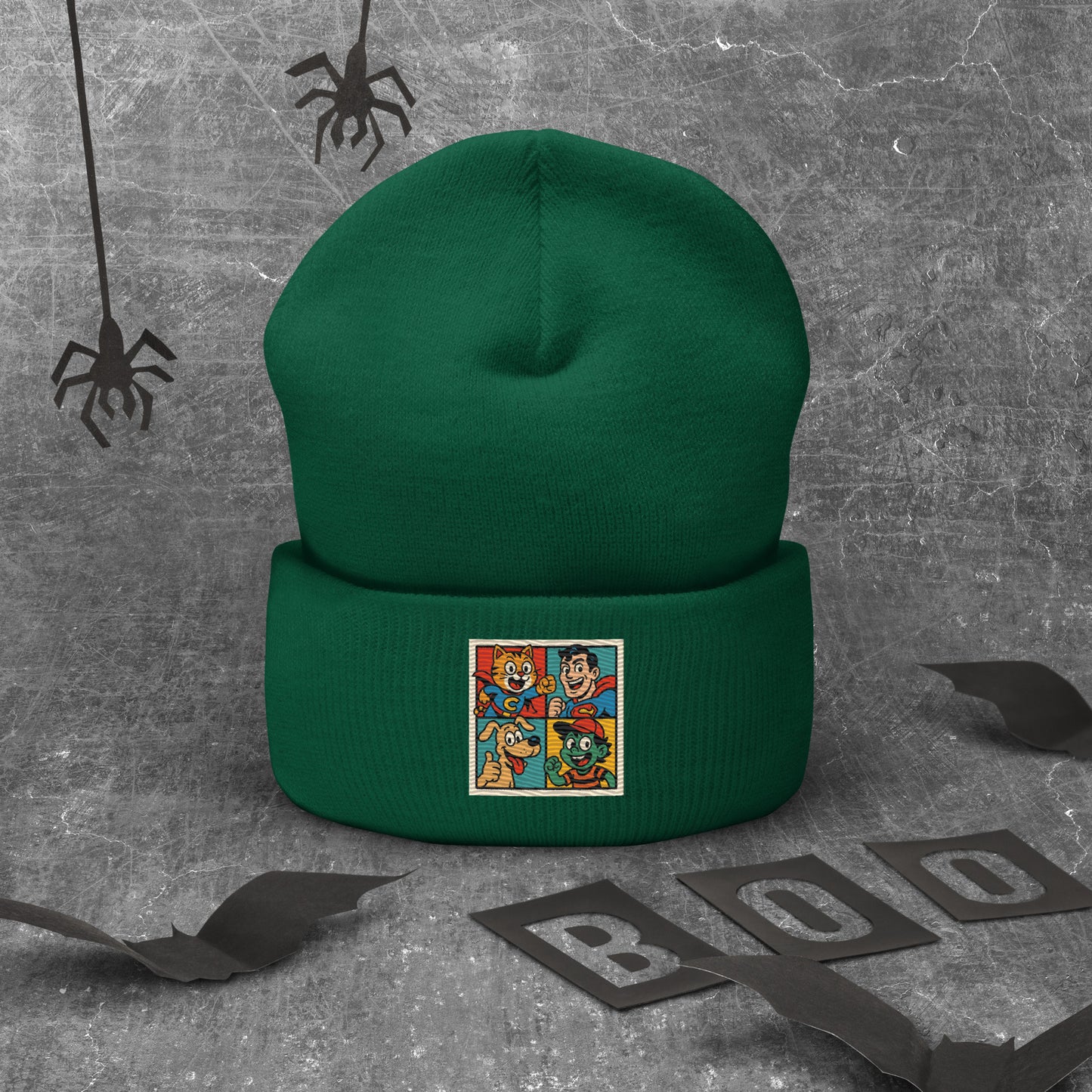 Green beanie with superhero design patch on a gray background with Halloween decorations.