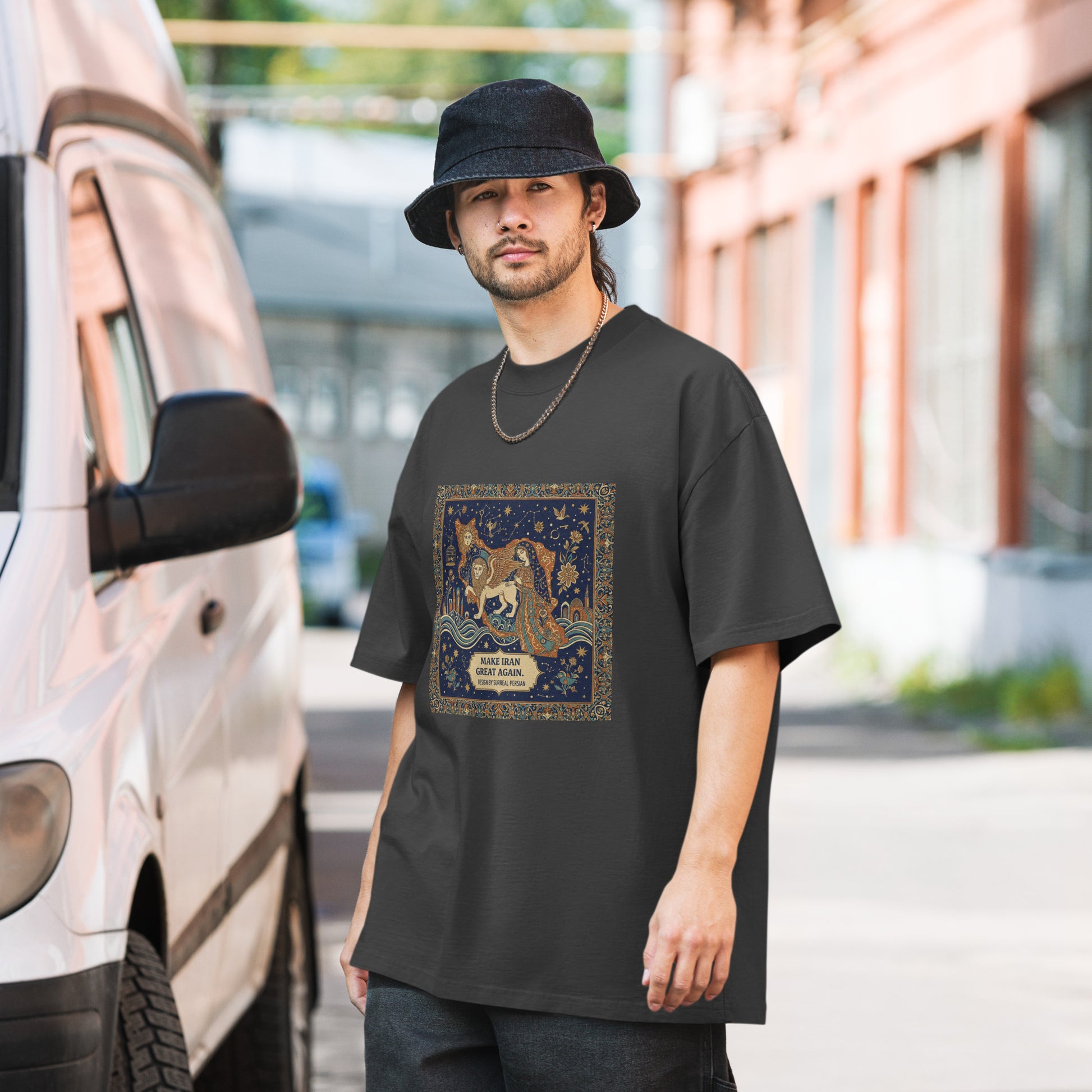 Man wearing a black t-shirt with a graphic design, standing next to a van.