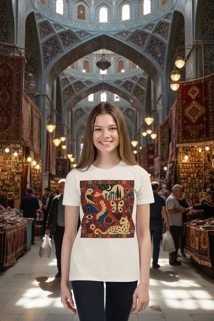 A young woman modeling a cream-colored t-shirt with a large, colorful, vintage-style graphic print on the front featuring snakes, butterflies, and a cat. She is wearing black pants against a solid white background.